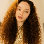 Artistic portrait of a woman with curly hair and soft expression indoors.